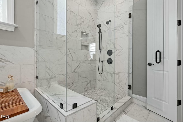 bathroom with marble finish floor, a stall shower, and a soaking tub