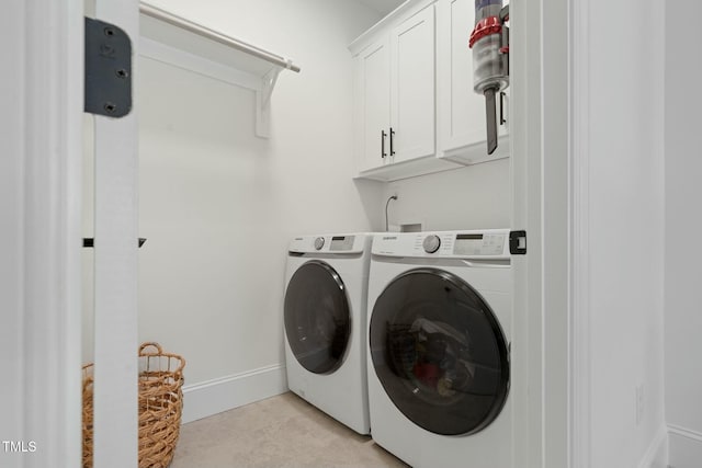 clothes washing area with washer and dryer, cabinet space, and baseboards