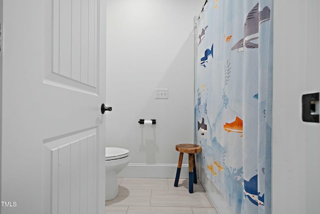 bathroom with baseboards, toilet, and a shower with curtain