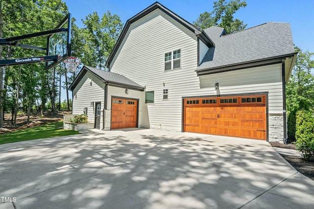 view of property exterior featuring a garage, a shingled roof, and concrete driveway