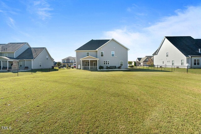 back of property with a sunroom and a lawn