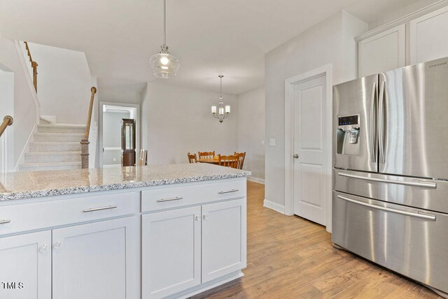 kitchen featuring pendant lighting, light hardwood / wood-style flooring, light stone countertops, white cabinets, and stainless steel refrigerator with ice dispenser