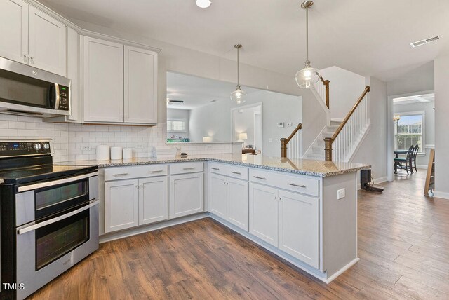 kitchen featuring kitchen peninsula, dark hardwood / wood-style floors, white cabinetry, and stainless steel appliances