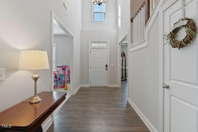 entrance foyer with dark wood-type flooring and a towering ceiling