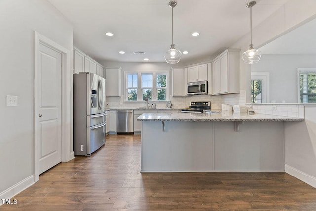 kitchen with appliances with stainless steel finishes, plenty of natural light, kitchen peninsula, and white cabinetry