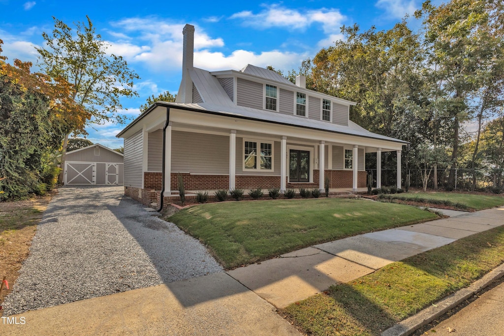 view of front of property featuring covered porch, a shed, and a front lawn