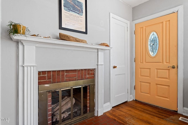 foyer with dark hardwood / wood-style floors and a brick fireplace