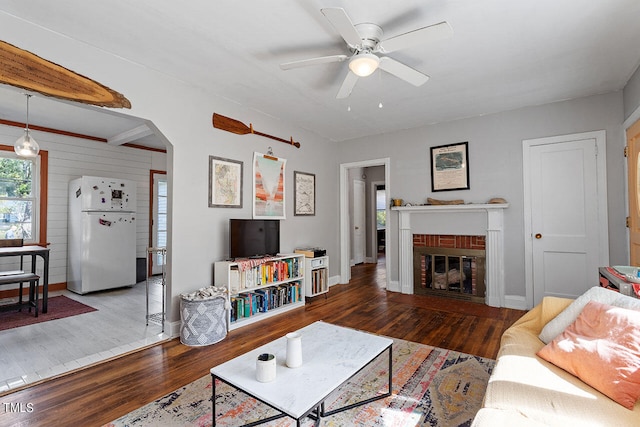 living room with dark wood-type flooring, a fireplace, and ceiling fan