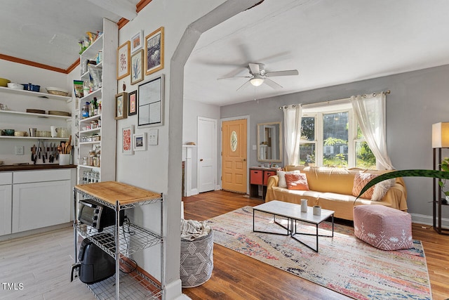 living room featuring light hardwood / wood-style floors, ornamental molding, and ceiling fan