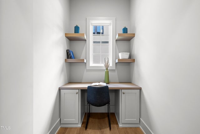office with built in study area, light wood-style floors, and baseboards