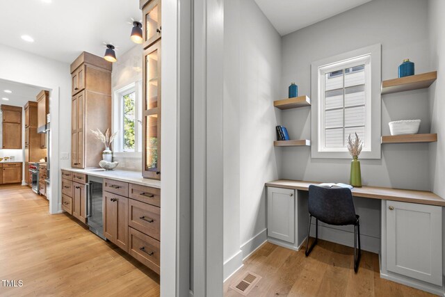 home office featuring beverage cooler, built in study area, light wood finished floors, recessed lighting, and baseboards
