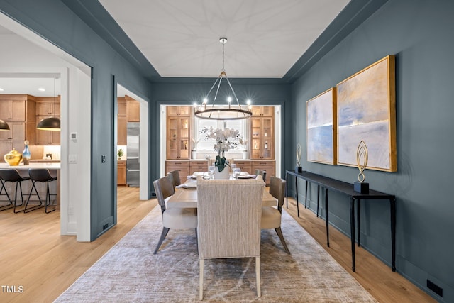 dining space with a chandelier, light wood finished floors, and baseboards