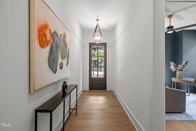 doorway featuring wood finished floors, baseboards, and ceiling fan