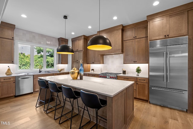 kitchen featuring stainless steel appliances, a kitchen island, light wood-style floors, tasteful backsplash, and light stone countertops