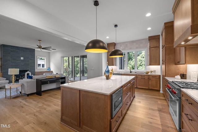 kitchen featuring appliances with stainless steel finishes, custom range hood, brown cabinetry, light wood-style flooring, and recessed lighting