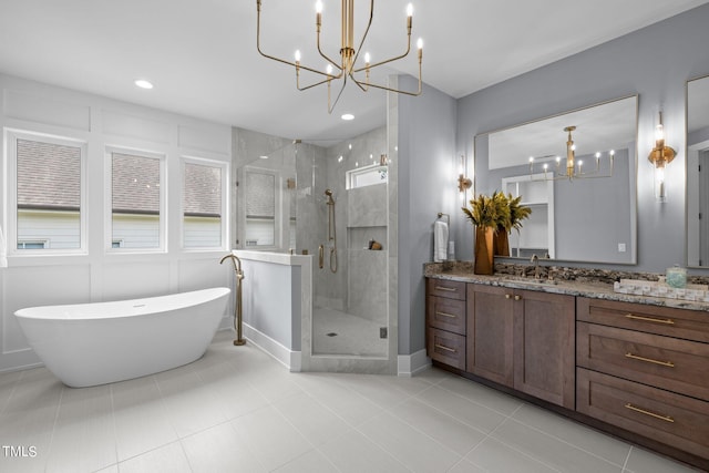bathroom featuring a chandelier, vanity, a stall shower, a freestanding bath, and tile patterned flooring
