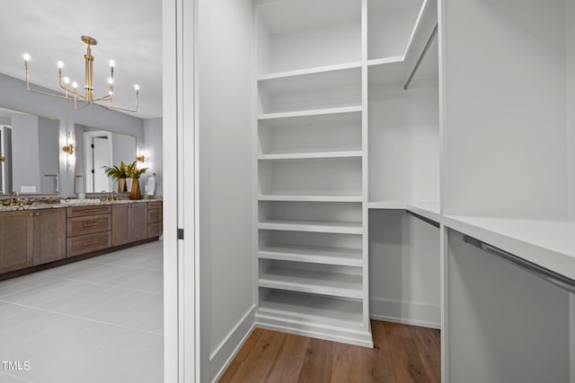 walk in closet featuring a chandelier, a sink, and light wood-type flooring