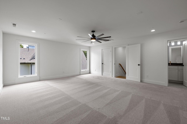 unfurnished bedroom featuring multiple windows, light colored carpet, baseboards, recessed lighting, and ceiling fan