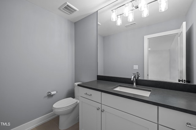 half bathroom with toilet, vanity, baseboards, and tile patterned flooring
