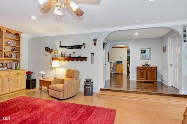 living area with ornamental molding, hardwood / wood-style floors, and ceiling fan