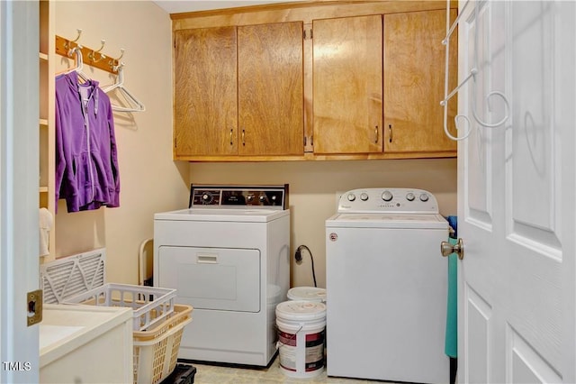 laundry area featuring washer and clothes dryer and cabinets