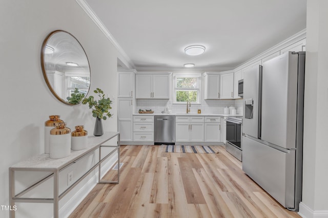 kitchen featuring sink, crown molding, white cabinetry, appliances with stainless steel finishes, and light hardwood / wood-style floors