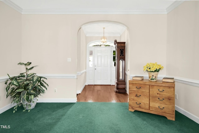 entryway featuring an inviting chandelier, ornamental molding, and carpet floors