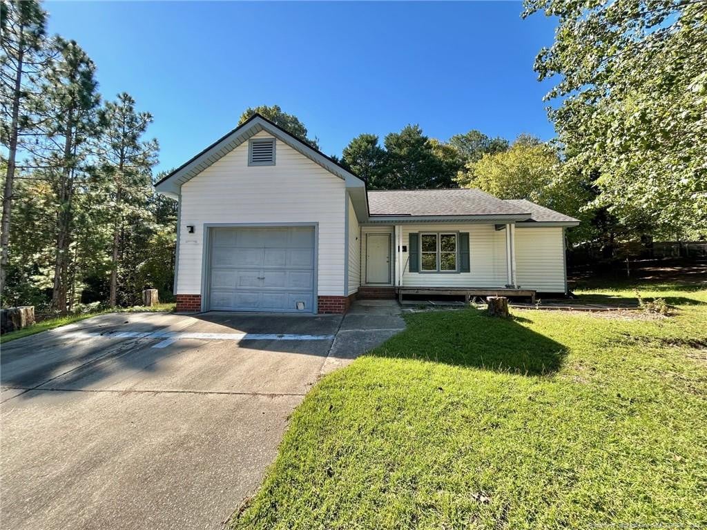 ranch-style house featuring a garage and a front lawn