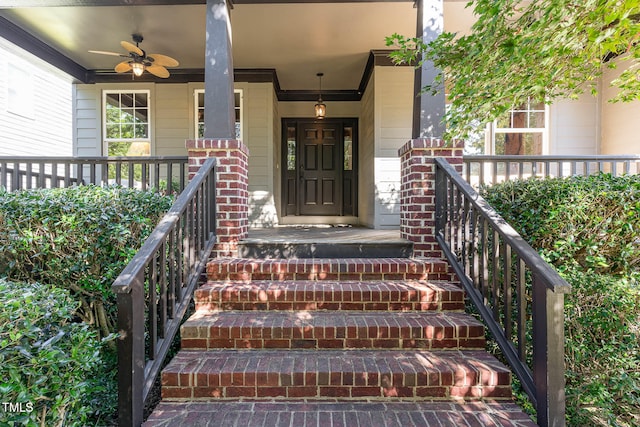 entrance to property with brick siding, a porch, and a ceiling fan