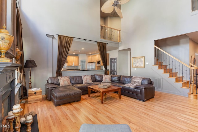 living room featuring a high ceiling, light hardwood / wood-style flooring, and ceiling fan