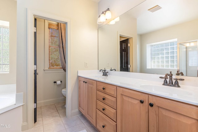 bathroom with double vanity, visible vents, a sink, and tile patterned floors