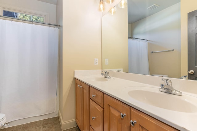 bathroom featuring visible vents, a sink, toilet, and double vanity