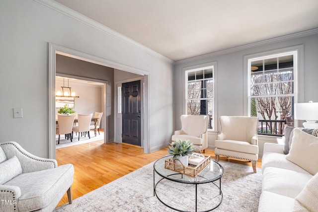 living area with ornamental molding, baseboards, and light wood finished floors