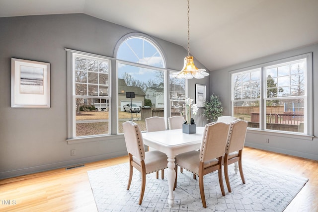 dining area featuring a healthy amount of sunlight, vaulted ceiling, and wood finished floors