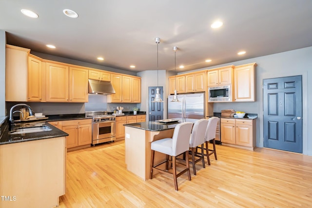 kitchen with under cabinet range hood, light brown cabinets, stainless steel appliances, and a sink