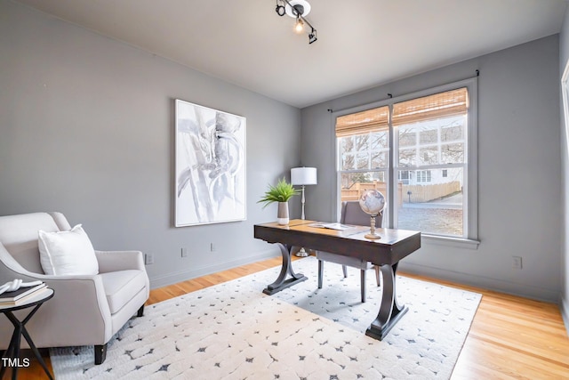 home office featuring track lighting, baseboards, and wood finished floors