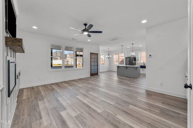 unfurnished living room with light hardwood / wood-style floors and ceiling fan with notable chandelier