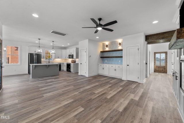 unfurnished living room with hardwood / wood-style flooring, sink, and ceiling fan