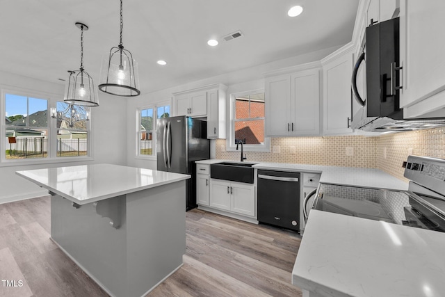 kitchen featuring dishwasher, white cabinetry, hanging light fixtures, and light wood-type flooring