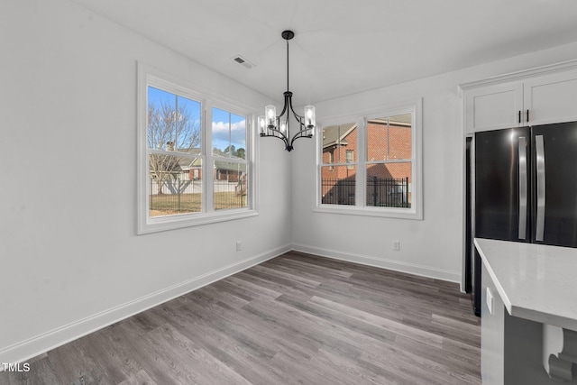 unfurnished dining area featuring light hardwood / wood-style floors and an inviting chandelier