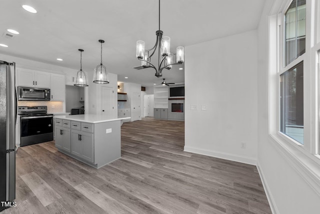 kitchen with electric range oven, a center island, hardwood / wood-style floors, white cabinetry, and decorative light fixtures