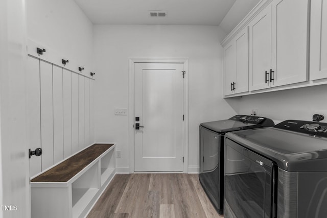 washroom with light hardwood / wood-style floors, cabinets, and washing machine and clothes dryer