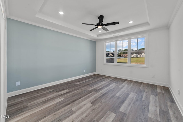 empty room featuring ornamental molding, hardwood / wood-style floors, a tray ceiling, and ceiling fan