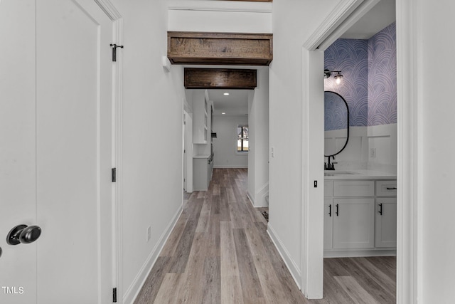 hallway with light hardwood / wood-style flooring and sink