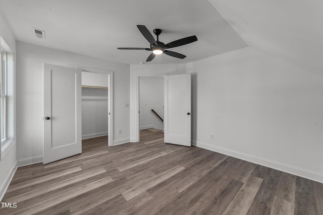 unfurnished bedroom with a spacious closet, multiple windows, hardwood / wood-style flooring, and ceiling fan