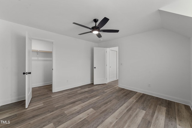 unfurnished bedroom featuring dark wood-type flooring, ceiling fan, a closet, and a spacious closet