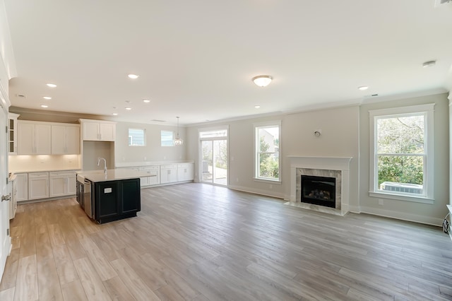 kitchen featuring a kitchen island with sink, light wood-type flooring, white cabinets, and plenty of natural light