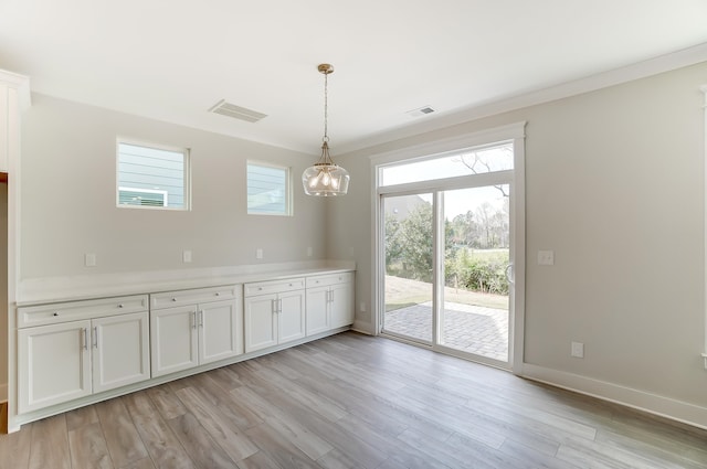 unfurnished dining area with a healthy amount of sunlight, ornamental molding, and light hardwood / wood-style flooring