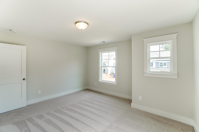 unfurnished room featuring light colored carpet and plenty of natural light