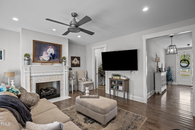 living room featuring a premium fireplace, dark hardwood / wood-style floors, and ceiling fan